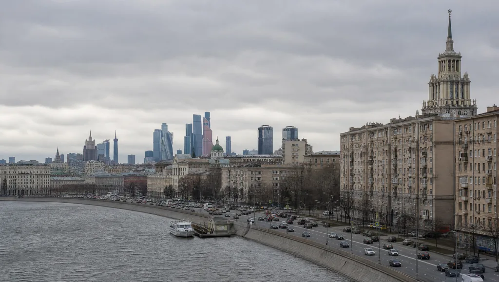 Городской вид России днём: набережная и дома под пасмурным небом